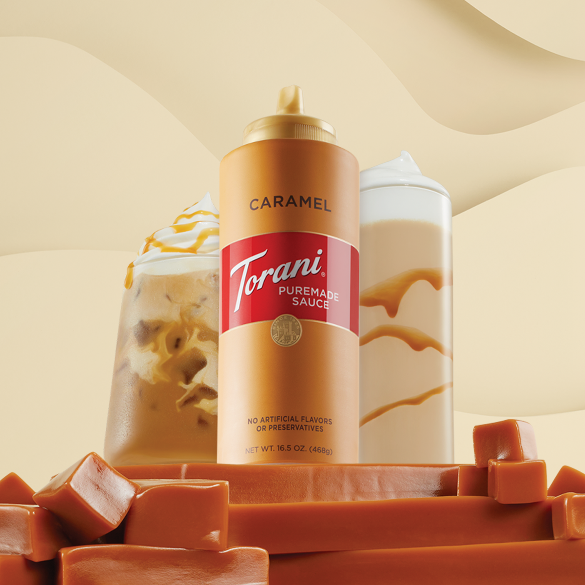 A bottle of Torani Puremade caramel sauce sitting heroically atop a mountain of caramel blocks flanked by two caramel coffee drinks